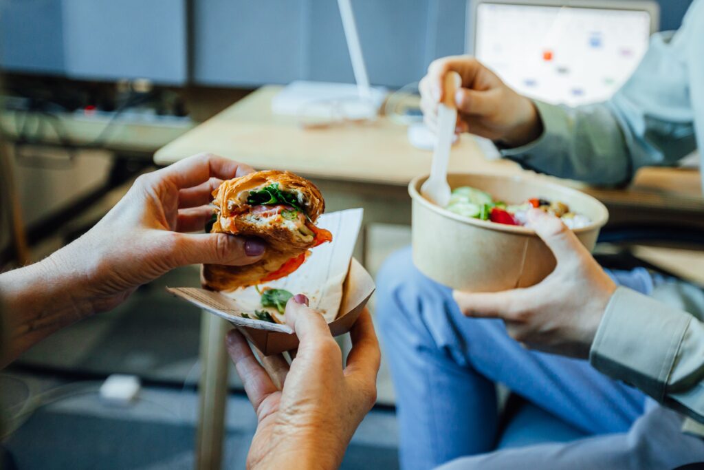 Donna con panino e bowl di insalata - pausa pranzo aziendale sana