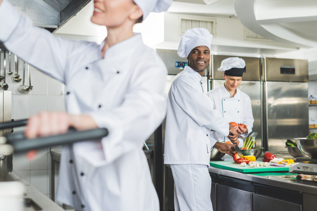 Chef multiculturali sorridenti cucinano in cucina da ristorante - ProntoPast